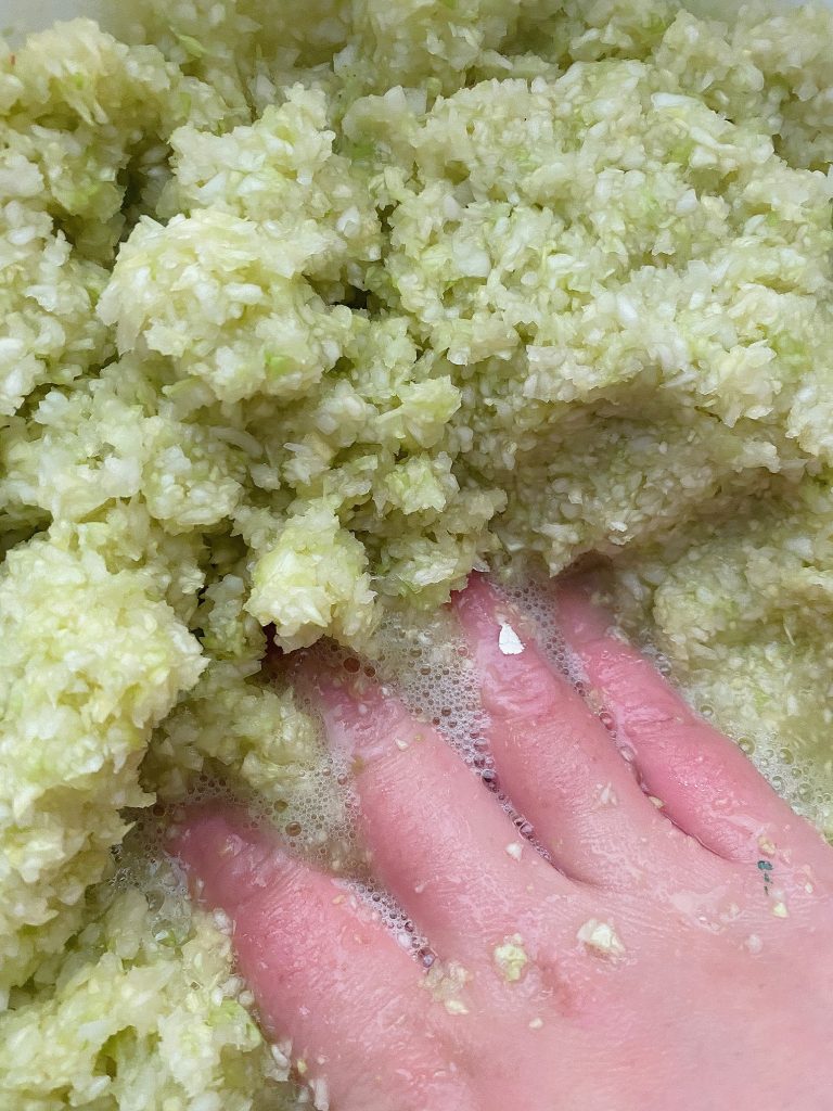hand mixing salt and cabbage to create brine solution