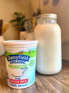 Stonyfield organic yogurt in fornt of half gallon mason jar filled with raw milk