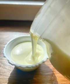 Yogurt being poured from a half gallon mason jar into small serving bowl