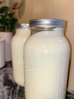 Two half gallon mason jars with raw milk, emphasizing the natural separation of cream