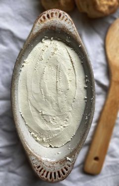 Shallow dish with raw milk cream cheese and wooden spoon in background